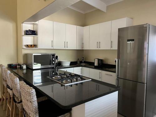 Una cocina con gabinetes blancos y un refrigerador de acero inoxidable. en Plumtree House, en Hoedspruit