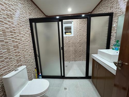 a bathroom with a shower and a toilet and a sink at International Haven Barili in Barili