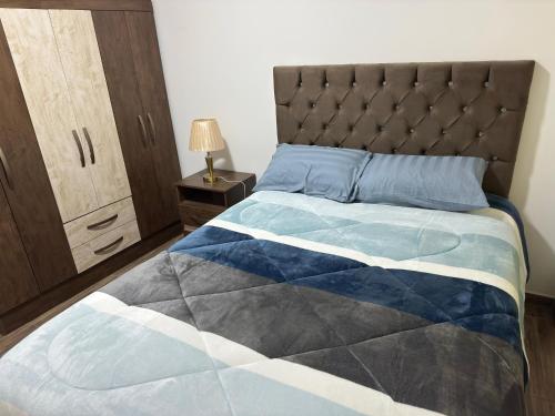 a bedroom with a bed with a blue and white quilt at Las Palmas Apart in Tacna