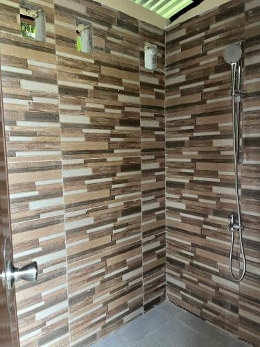 a bathroom with a shower with a wooden wall at International Haven Barili in Barili