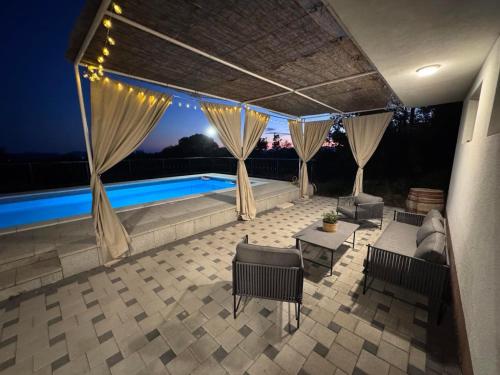 a patio with a canopy and a pool at night at Olives Garden in Čitluk