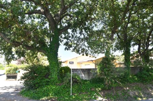 a tree with a sign in front of a house at Repos et Tranquillité - Super Calme de la campagne - Clim - Grande Piscine Partagée au Sel - Déco cosy tout confort in Montélimar