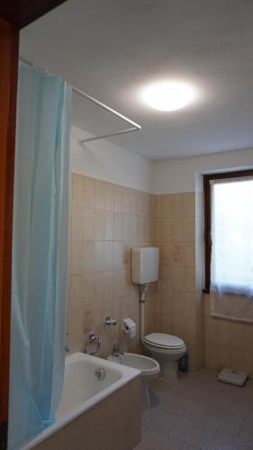 a bathroom with a toilet and a tub and a sink at The Heritage Home in Novate Mezzola