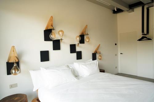 サン・マルチェッロにあるB&B Panevìのベッドルーム1室(壁に照明付きの白いベッド1台付)