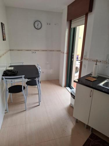 a kitchen with a table and chairs and a clock on the wall at Piso DJC in O Pedrouzo