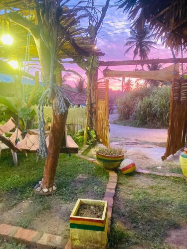 a garden with a palm tree and a pergola at Roxy in Tangalle