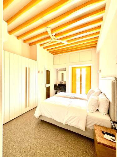a bedroom with a large white bed with a wooden ceiling at Callisso Mykonos in Mikonos