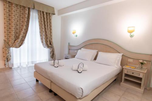 a bedroom with a large white bed and a window at Toscana Wellness Resort in Arcidosso
