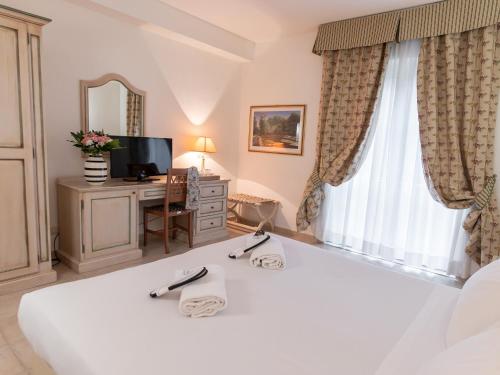 a bedroom with a white bed and a window at Toscana Wellness Resort in Arcidosso