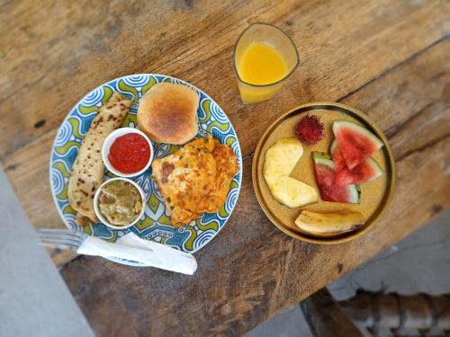 a table with a plate of breakfast food and a bowl of fruit at AFYA Village at the sea in Michamvi
