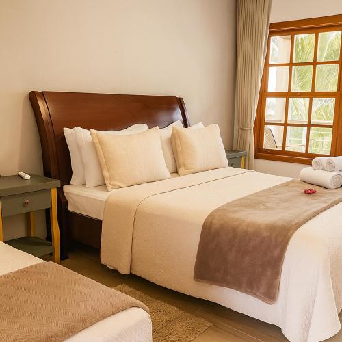 a hotel room with two beds and a window at Pousada Flores do Cerrado in Pirenópolis