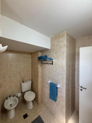 a bathroom with a toilet and a shower with blue towels at Departamento centrico Avenida Cordoba Edificio Campanarios XIX in Esperanza