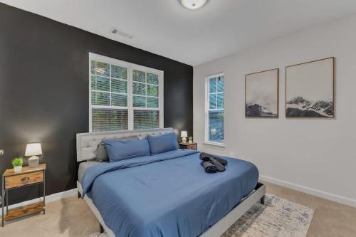 Un dormitorio con una cama azul y dos ventanas. en Upscale King 2BR Suite Mins to Downtown Raleigh, en Cary