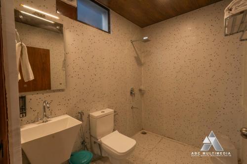 a bathroom with a white toilet and a sink at CASA Resort and Restaurant in Rāmnagar
