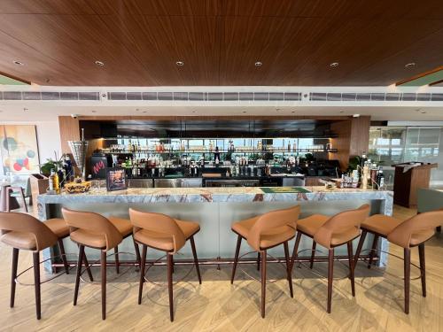 a bar in a restaurant with brown stools at Ramada Encore by Wyndham Gurugram Dwarka Expressway in Gurgaon