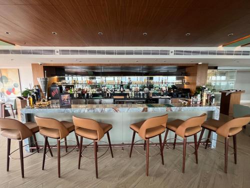 a bar in a restaurant with chairs around it at Ramada Encore by Wyndham Gurugram Dwarka Expressway in Gurgaon