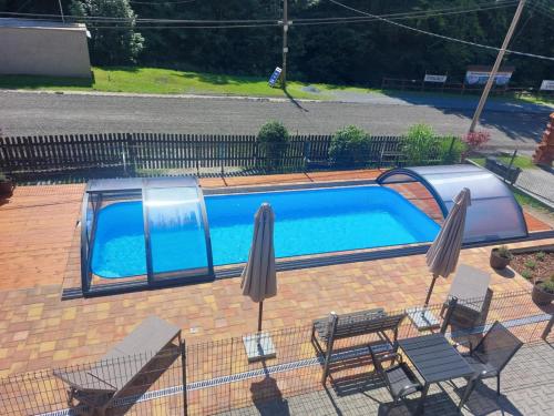 a swimming pool with two chairs and two umbrellas at U Veselé lišky in Hutisko
