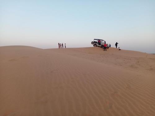 a group of people standing on top of a sand dune at Osian Camel safari and Village home stay in Gheura