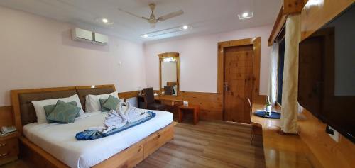 a bedroom with a large bed and a television at Quartz Himalayan Brothers in Dharamshala