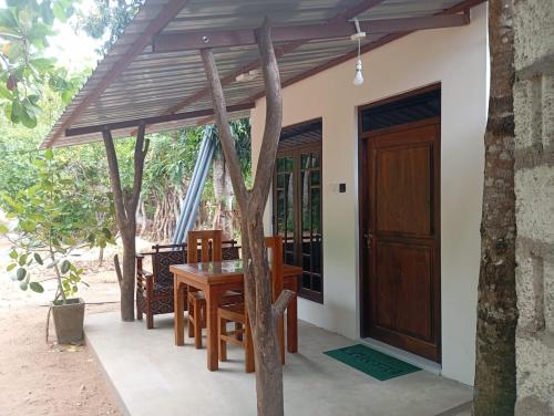 a house with a wooden table and a wooden door at Wilpattu Buma Lodge in Pahala Maragahawewa