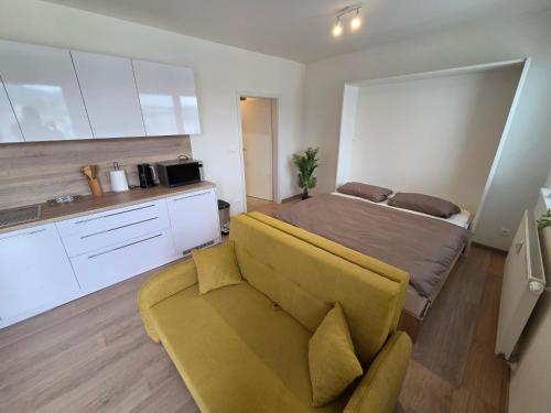 a bedroom with a bed and a yellow couch at Apartmán RETRO in Žilina