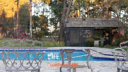 a table and chairs next to a swimming pool at Sitio em Sarapui com piscina e lareira in Sarapuí