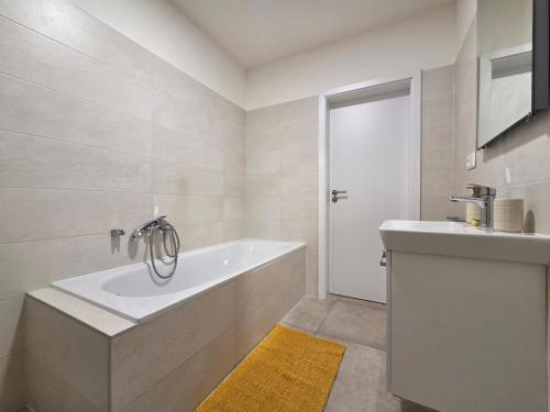 a white bathroom with a tub and a sink at Apartmán RETRO in Žilina