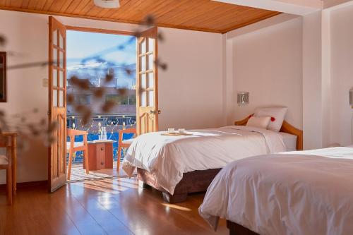 a bedroom with two beds and a sliding glass door at Maimara Hotel in Huaraz