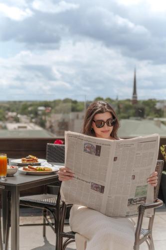 a woman sitting in a chair reading a newspaper at The Virginian Lynchburg, Curio Collection By Hilton in Lynchburg