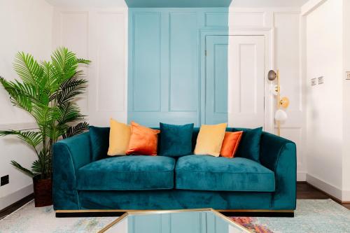 a blue couch with colorful pillows in a living room at Design Haven! Big Group-Friendly 4BR City Escape in Waterloo's Coolest Corner in London
