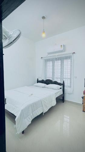 a bedroom with a large bed in a white room at Kanaan Homestay in Munroe Island