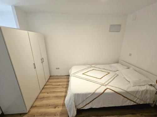 a small white bedroom with a bed and cabinets at Peaceful Poolside Studio 20min from BCN in Sant Cugat del Vallès