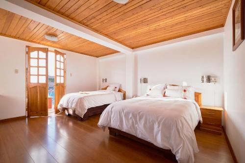 a bedroom with two beds and a wooden ceiling at Maimara Hotel in Huaraz