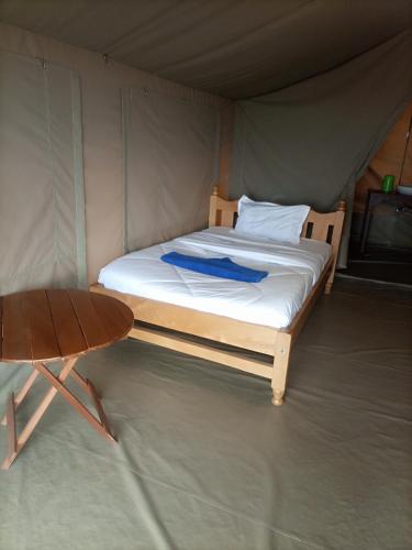 Bett in einem Zelt mit einem Holztisch in der Unterkunft Sote Safaris in Narok