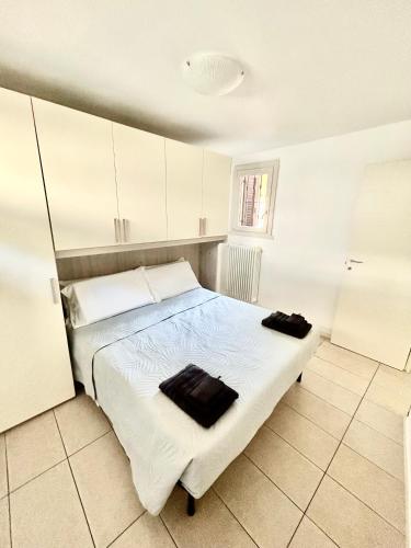 a bedroom with a white bed with two black towels on it at Casa Imelde al lago in Onno
