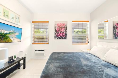 a white bedroom with a large bed and some windows at Central Miami Beach Condo w BBQ Facilities in Miami Beach