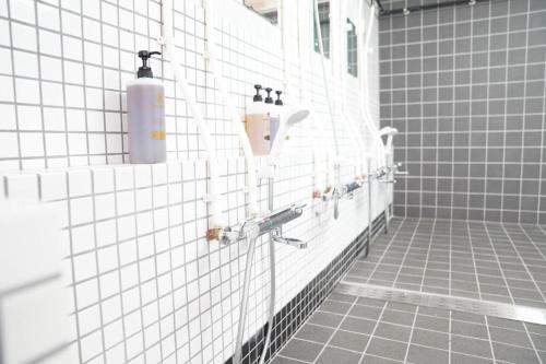 a white tiled bathroom with a soap dispenser on the wall at 心斎橋難波関空直通Ambers 7708 in Osaka