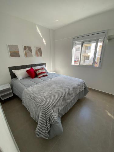 a white bedroom with a large bed with red pillows at Apto Novo próximo ao centro ap 2 quartos in Serra Negra