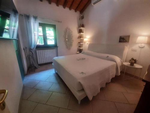 a white bedroom with a bed and a window at La casa di Priscilla in Bucine