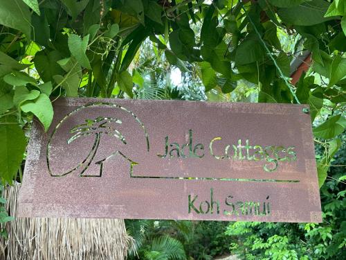 a sign hanging from a tree with a palm tree at Jade cottages in Bophut