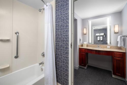 a bathroom with a tub and a sink and a mirror at Homewood Suites by Hilton Dulles-North Loudoun in Ashburn