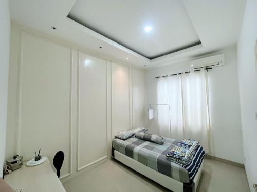 a bedroom with a bed in a room with white walls at White House Private Room at PIK in Jakarta