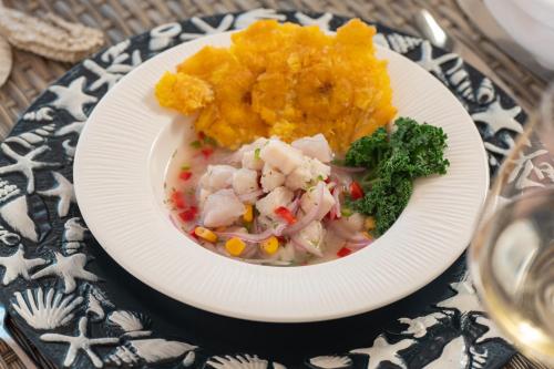 a white plate of food with vegetables on a table at Hotel Agua Azul Beach Resort in Baru