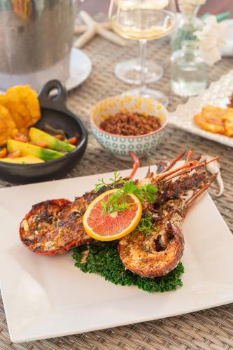 a plate of food with shrimp and an orange slice at Hotel Agua Azul Beach Resort in Baru