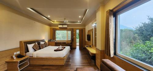 a bedroom with a bed and a large window at Quartz Himalayan Brothers in Dharamshala