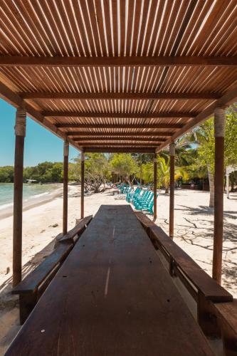 a wooden picnic table on a beach with benches at Hotel Agua Azul Beach Resort in Baru