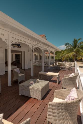 a wooden deck with wicker chairs and tables at Hotel Agua Azul Beach Resort in Baru