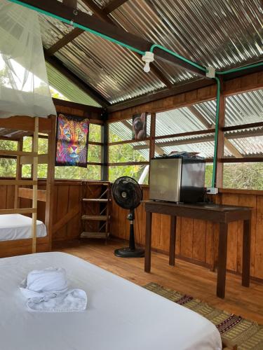 1 dormitorio con 1 cama, TV y ventilador en Cabañas Mashcopiro Amazonas, en Puerto Nariño