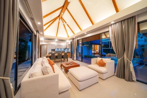 a living room with white furniture and a dining room at BangTao Anchan 豪华两卧 私人泳池 现代度假巴厘风 in Layan Beach