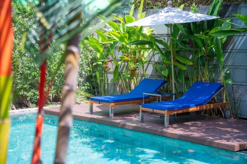 two blue chairs and an umbrella next to a pool at BangTao Anchan 豪华两卧 私人泳池 现代度假巴厘风 in Layan Beach